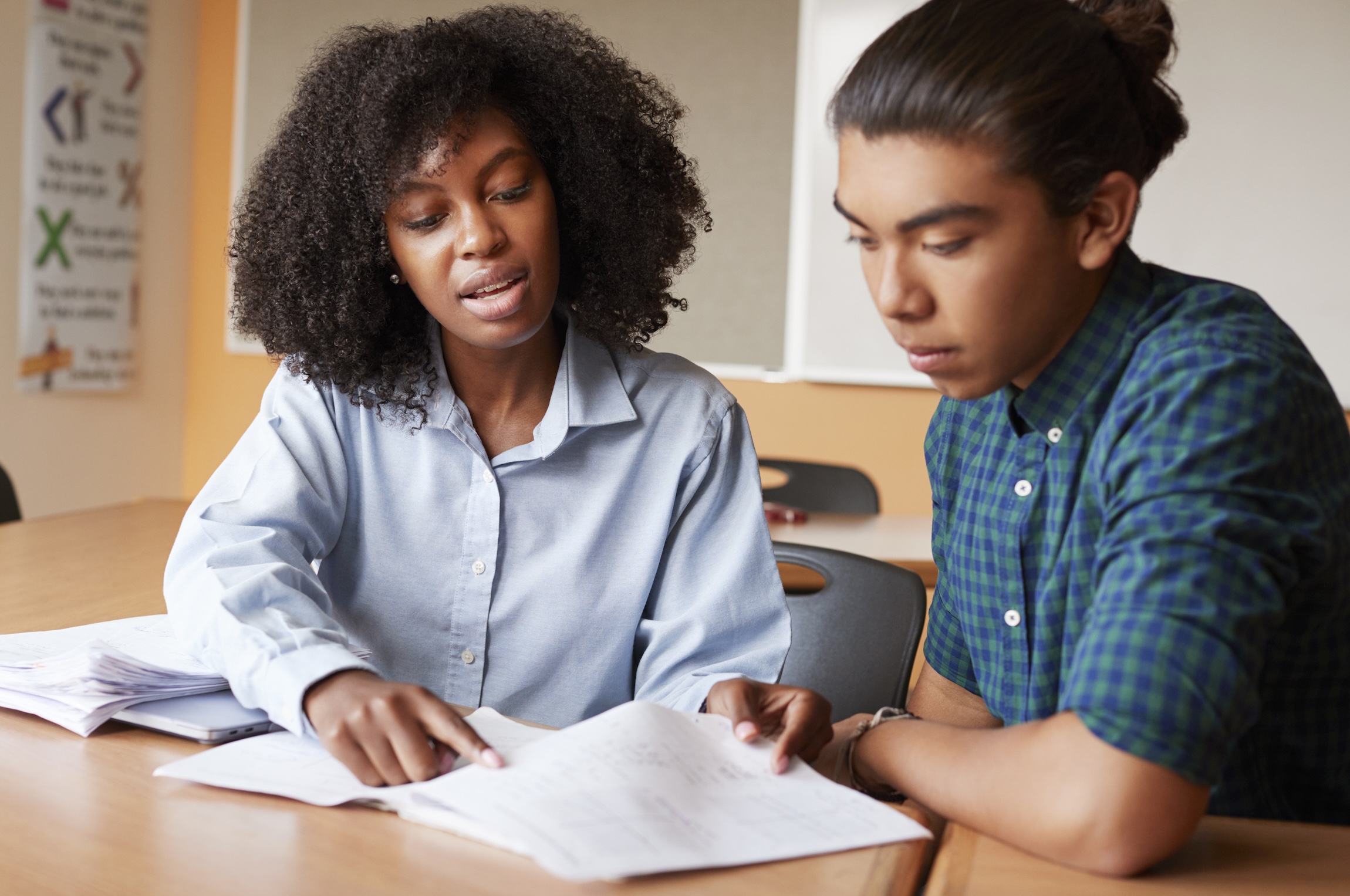 High School Tutor Giving Male Student One To One Tutoring At Desk